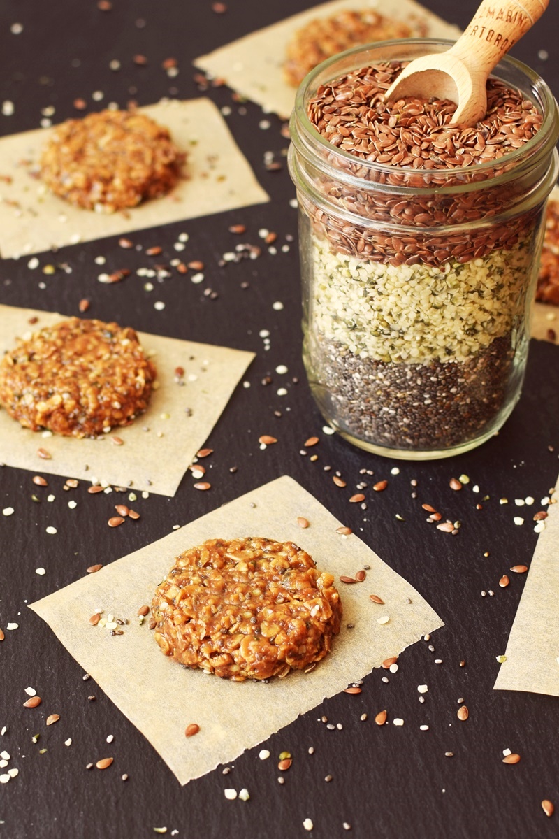 No-bake power cookies on parchment squares with a mason jar filled with hem, chia and sesame seeds